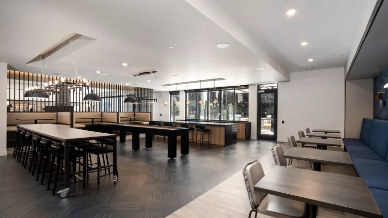 spacious, modern common room with a billiards table, communal table, and lounge seating.